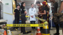 Visitantes em uma cena de crime simulada.
