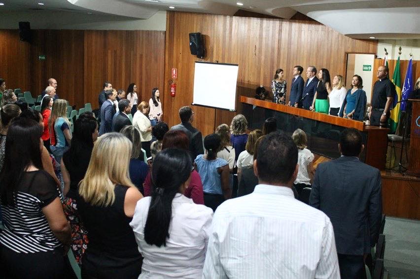 Pessoas de pé em auditório participam do lançamento do Projeto Pilares