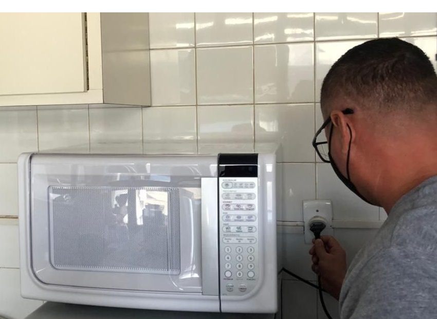 homem, técnico, ligando micro-ondas na tomada