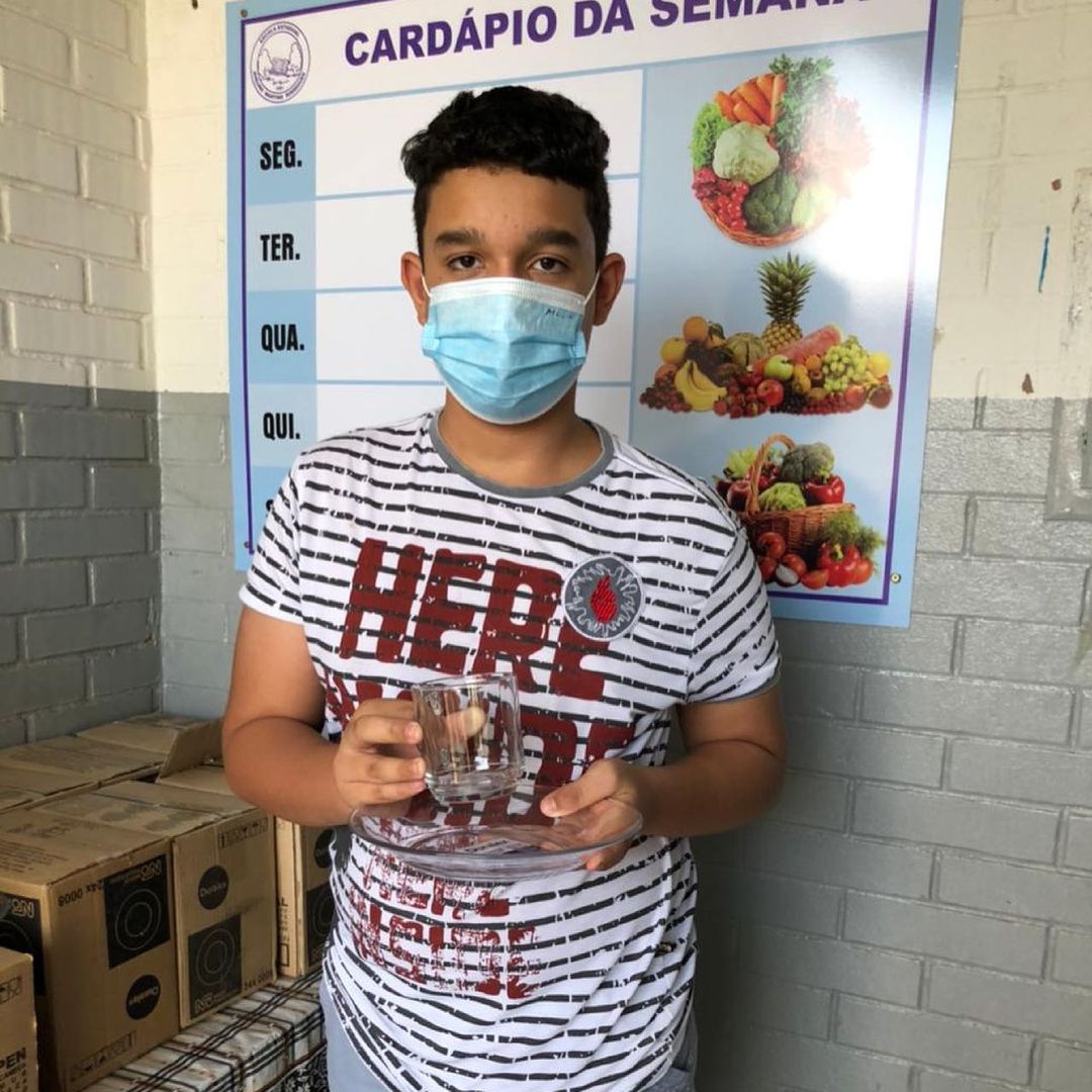 Estudante da Escola Estadual Avelino Martins Rodrigues segurando caneca e prato de vidro