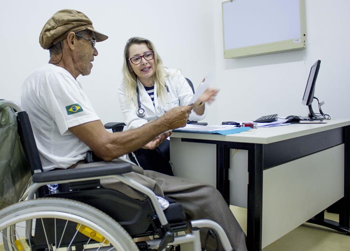 Paciente idoso e cadeirante sendo atendido por médica do HDS.