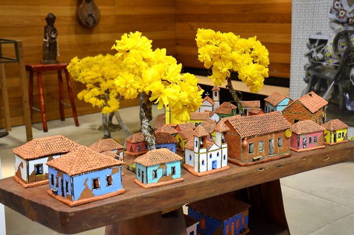 Típicas casas de taipa e adobe e atrás delas Ipês amarelos, cenário muito comum nas zonas rurais de Goiás, retratado pelo artesão Vilmar, de Goiânia.
