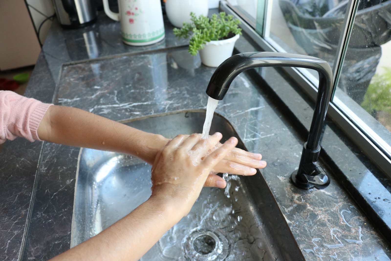 Saneago alerta para uso consciente da água durante período de seca - mãos femininas sob torneira aberta em pia de cozinha